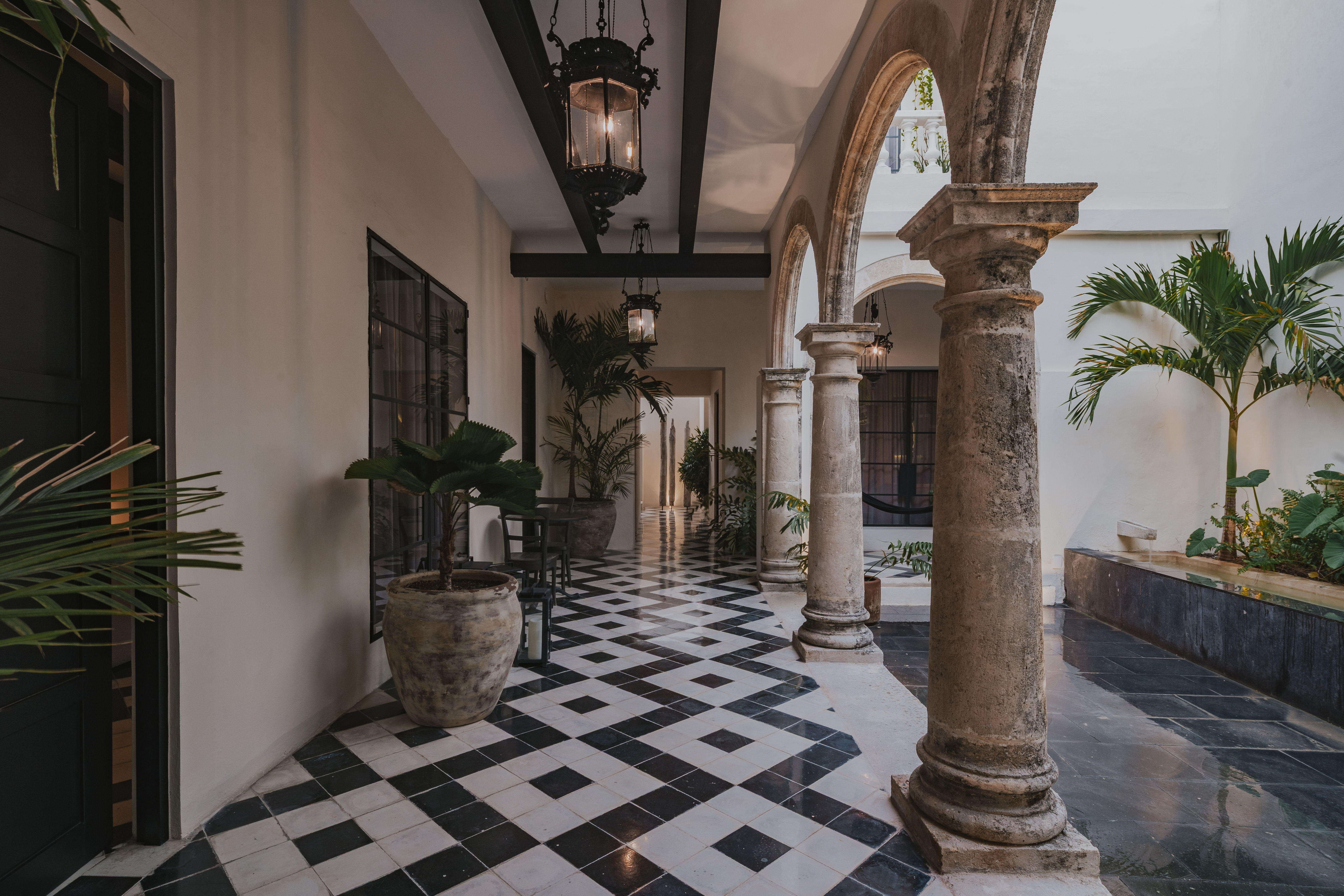 Corredor interior con palmera y piso de damero en Casa Japa — arquitectura colonial restaurada en Campeche